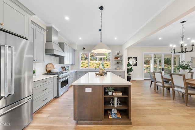 kitchen featuring light wood-type flooring, custom range hood, premium appliances, pendant lighting, and a center island