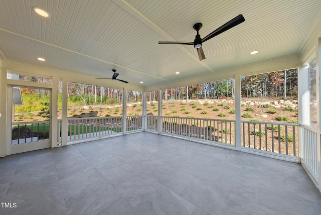 unfurnished sunroom featuring ceiling fan, a healthy amount of sunlight, and wood ceiling