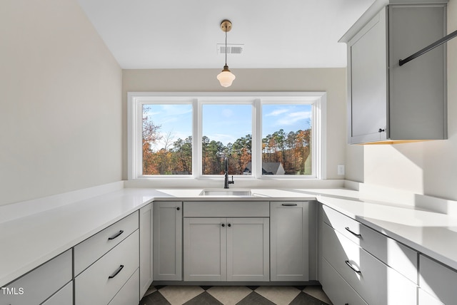 kitchen with gray cabinetry, decorative light fixtures, and sink