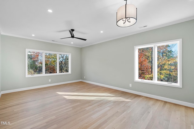 empty room featuring ceiling fan, a healthy amount of sunlight, crown molding, and light hardwood / wood-style flooring