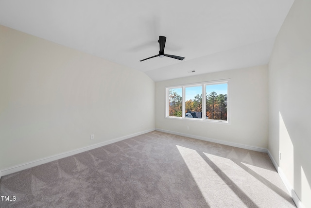 spare room featuring ceiling fan, light colored carpet, and vaulted ceiling