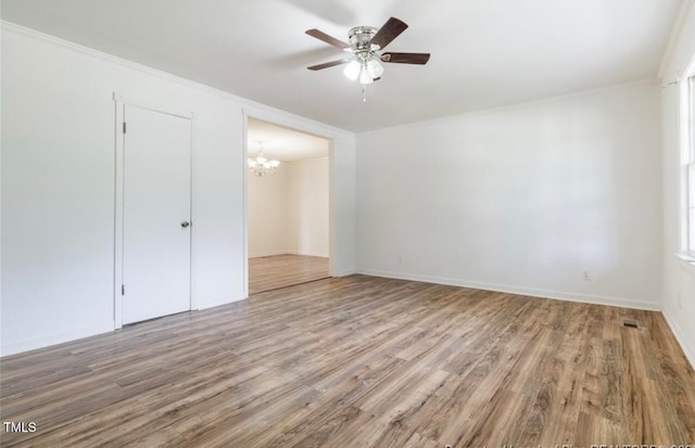 unfurnished bedroom with crown molding, a closet, wood-type flooring, and ceiling fan with notable chandelier