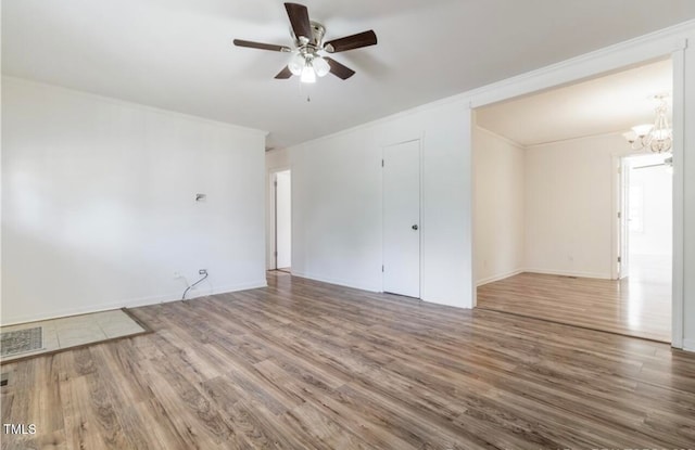 spare room featuring ceiling fan with notable chandelier, wood-type flooring, and crown molding