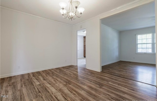 unfurnished room featuring dark hardwood / wood-style floors, crown molding, and a notable chandelier