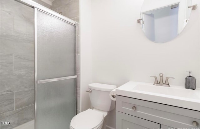 bathroom with vanity, a shower with shower door, and toilet