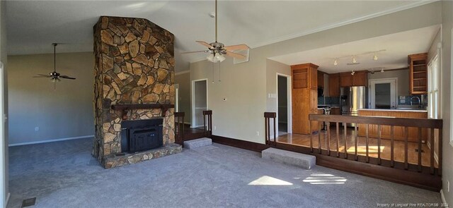 living room featuring carpet flooring, vaulted ceiling, ceiling fan, and a stone fireplace