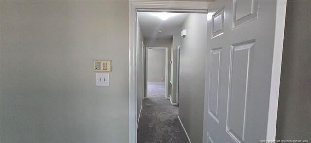 hallway with dark colored carpet