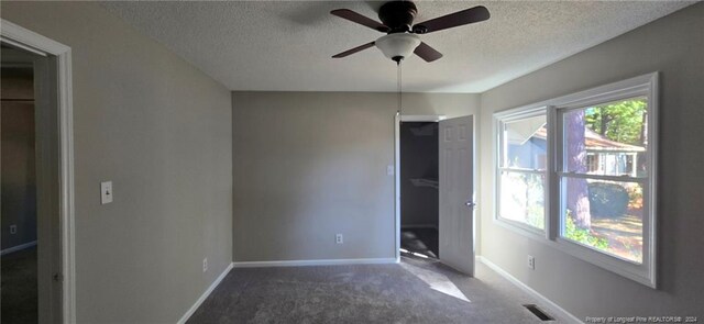 unfurnished bedroom featuring ceiling fan, carpet floors, a textured ceiling, and a closet