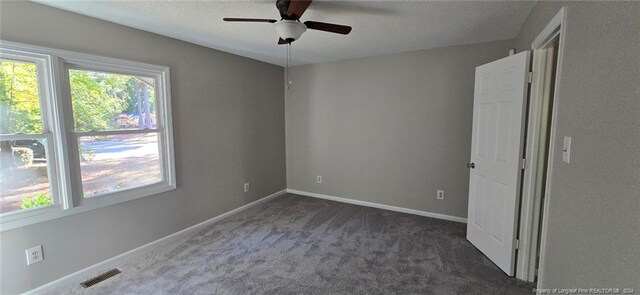 spare room with dark colored carpet and ceiling fan