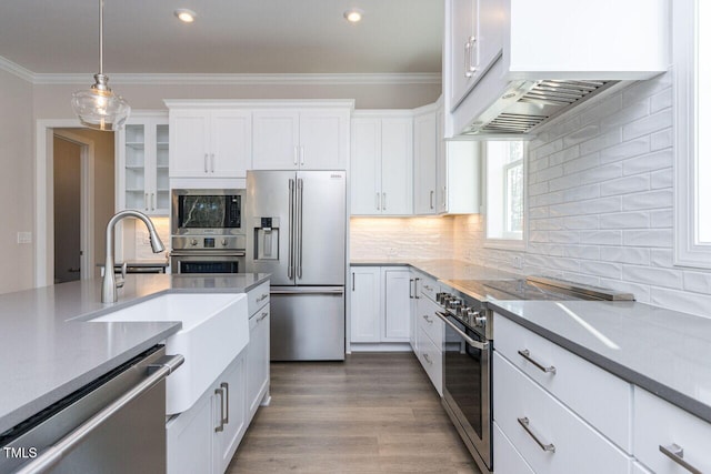 kitchen featuring high end appliances, backsplash, white cabinetry, and crown molding