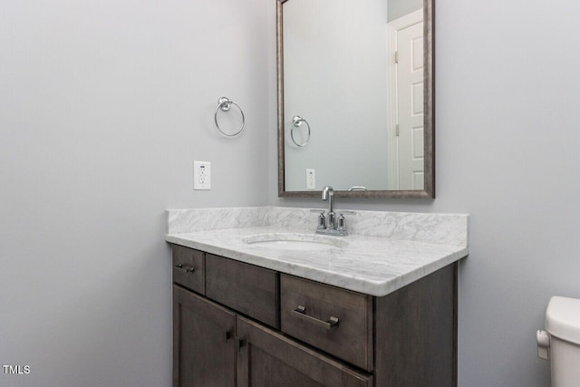 half bathroom featuring vanity and toilet