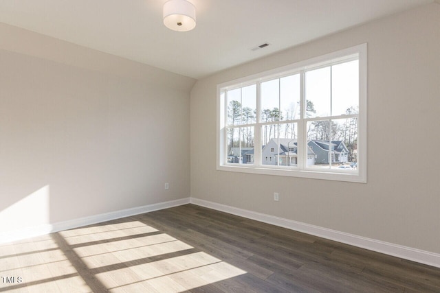 empty room with visible vents, baseboards, and dark wood finished floors