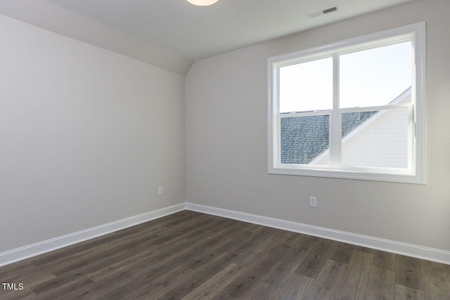 empty room featuring vaulted ceiling, dark wood-style flooring, visible vents, and baseboards