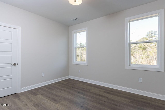 spare room with baseboards, visible vents, and dark wood finished floors