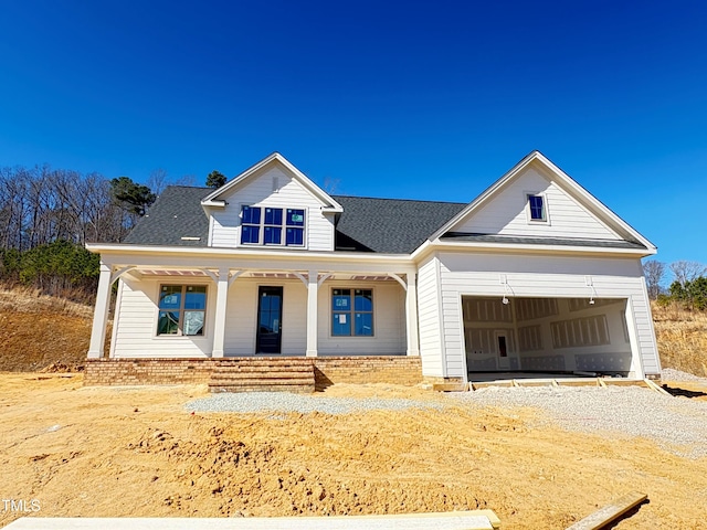 modern farmhouse style home with covered porch, roof with shingles, driveway, and an attached garage