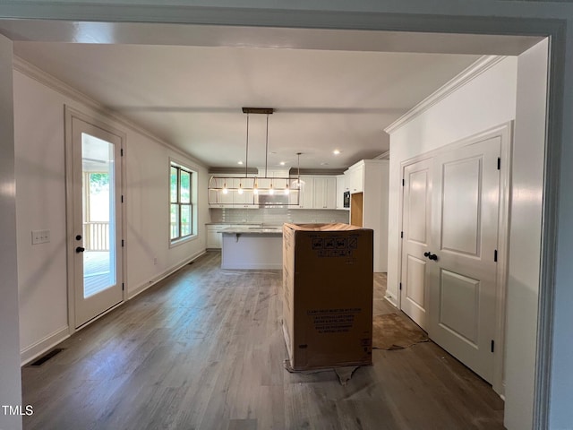 6040 Scalybark Rd, Durham, NC 27712 - kitchen with crown molding, a center island, wood finished floors, white cabinetry, and backsplash