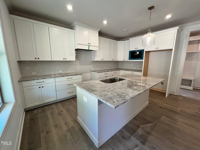 6040 Scalybark Rd, Durham, NC 27712 - kitchen featuring black microwave, white cabinetry, a center island with sink, light stone countertops, and backsplash