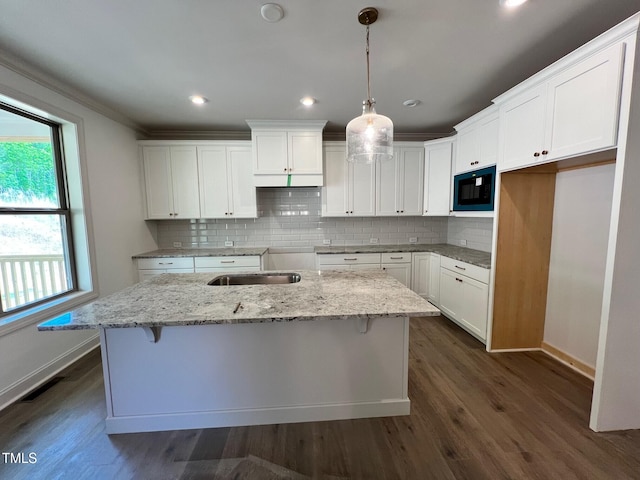 6040 Scalybark Rd, Durham, NC 27712 - kitchen with black microwave, baseboards, an island with sink, decorative backsplash, and ornamental molding