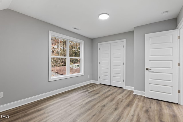 unfurnished bedroom with light hardwood / wood-style floors, a closet, and lofted ceiling