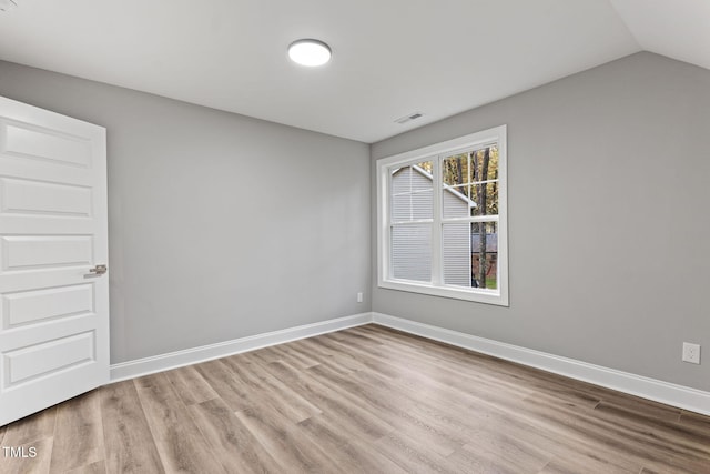 spare room featuring lofted ceiling and light wood-type flooring