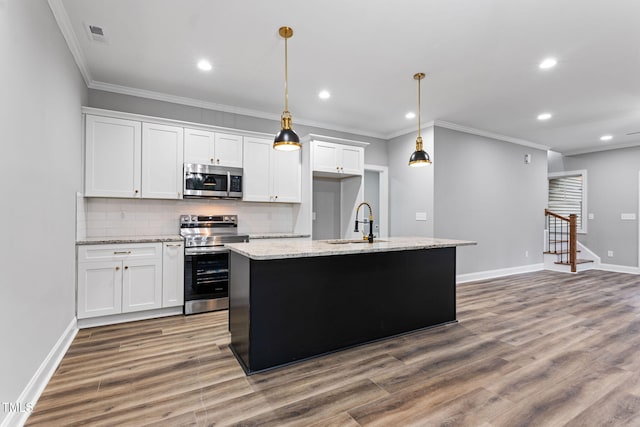 kitchen featuring white cabinets, appliances with stainless steel finishes, and a center island with sink