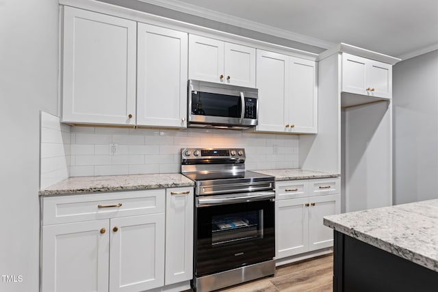 kitchen with white cabinets, decorative backsplash, ornamental molding, light hardwood / wood-style floors, and stainless steel appliances