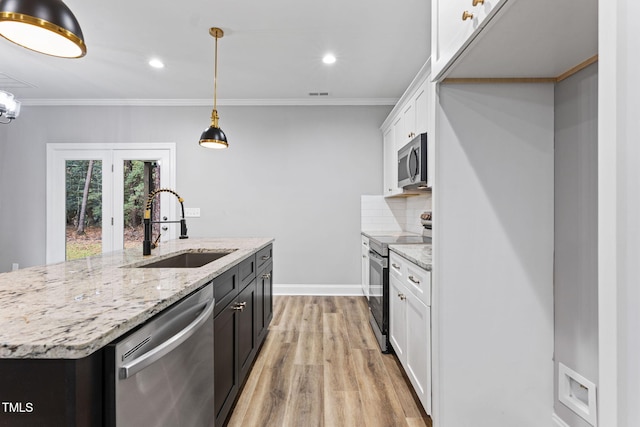 kitchen featuring light wood-type flooring, stainless steel appliances, sink, decorative light fixtures, and white cabinets