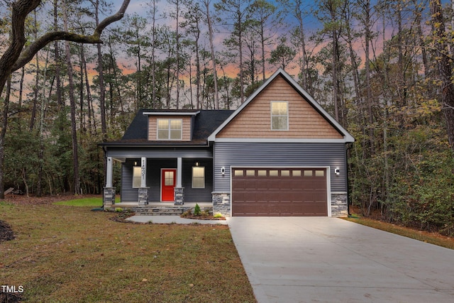 view of front of house with covered porch, a yard, and a garage