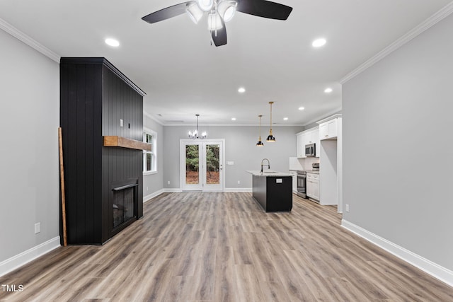 unfurnished living room featuring ceiling fan with notable chandelier, sink, crown molding, and light hardwood / wood-style flooring