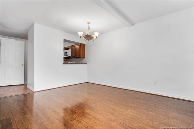 empty room featuring beamed ceiling, a chandelier, and hardwood / wood-style flooring