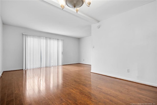 empty room with beam ceiling and wood-type flooring