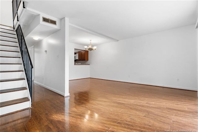 unfurnished living room with dark hardwood / wood-style flooring and a chandelier