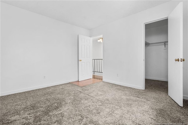 unfurnished bedroom with carpet flooring, a spacious closet, and a closet