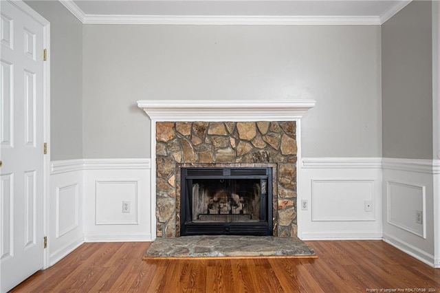 interior details featuring a stone fireplace, wood-type flooring, and crown molding