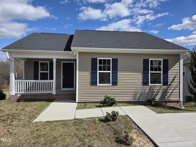 view of front of home with a porch, roof with shingles, and a front lawn