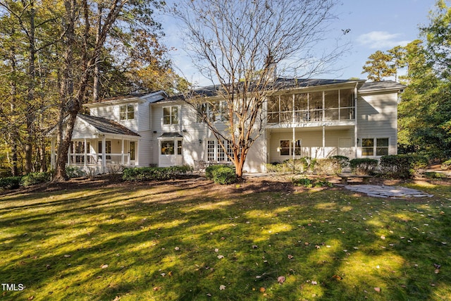 back of property with a sunroom and a yard