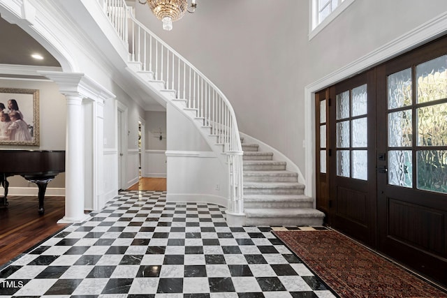 entrance foyer featuring french doors, dark wood-type flooring, a notable chandelier, crown molding, and a towering ceiling