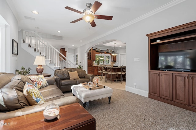 carpeted living room with ceiling fan and crown molding