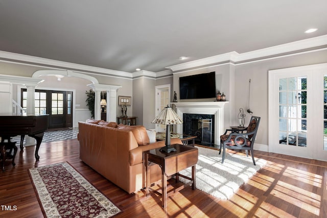 living room with hardwood / wood-style floors, plenty of natural light, crown molding, and a premium fireplace