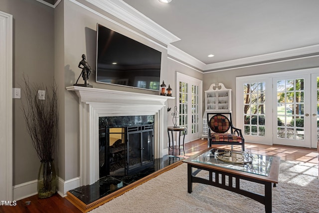 living room featuring hardwood / wood-style floors, crown molding, a high end fireplace, and french doors