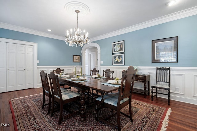 dining area featuring ornamental molding, dark wood-type flooring, and a chandelier