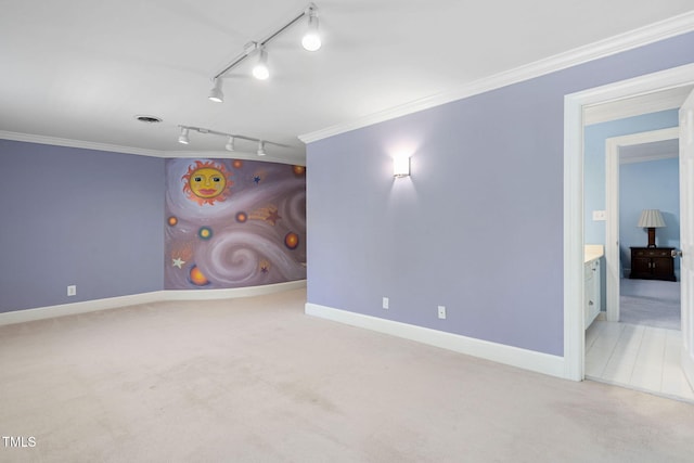 carpeted spare room featuring track lighting and ornamental molding