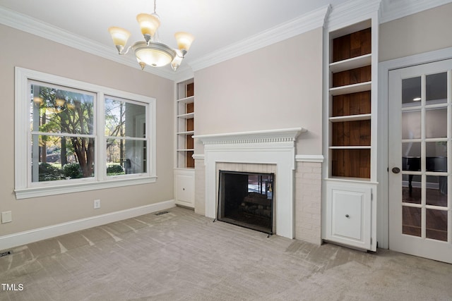 unfurnished living room featuring built in shelves, a brick fireplace, an inviting chandelier, light colored carpet, and ornamental molding