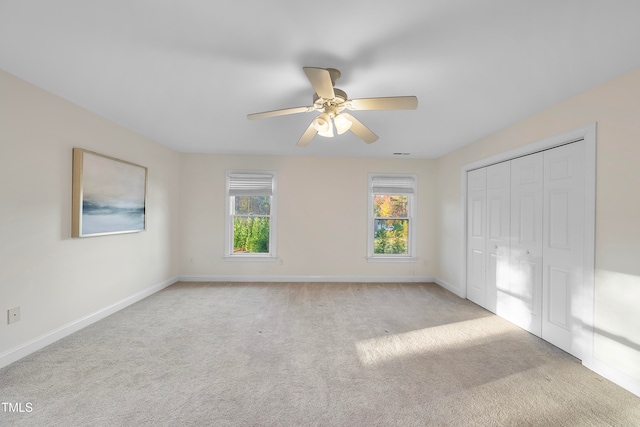 unfurnished bedroom featuring ceiling fan, a closet, and light colored carpet