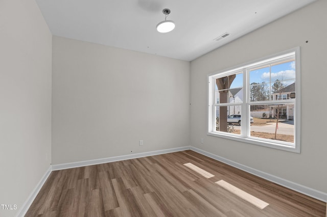 empty room with visible vents, baseboards, and wood finished floors