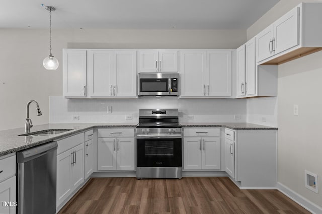 kitchen featuring appliances with stainless steel finishes, white cabinets, a sink, and decorative light fixtures