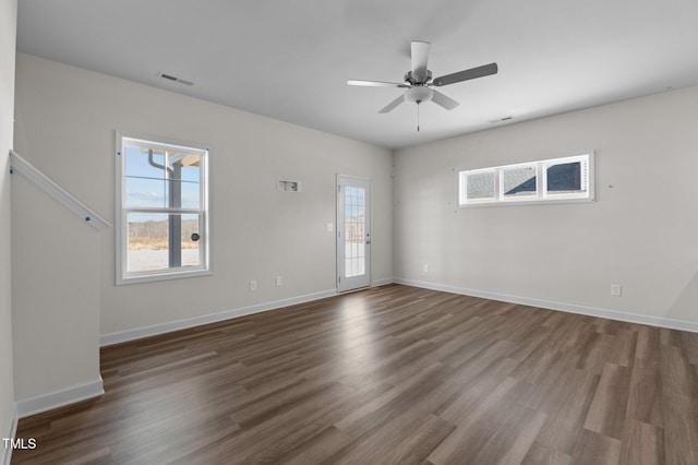 empty room featuring a ceiling fan, dark wood-style flooring, visible vents, and baseboards