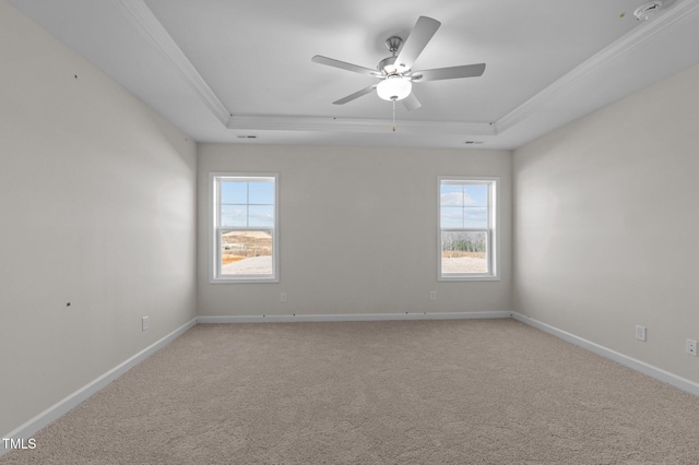 carpeted spare room featuring a ceiling fan, a raised ceiling, and baseboards