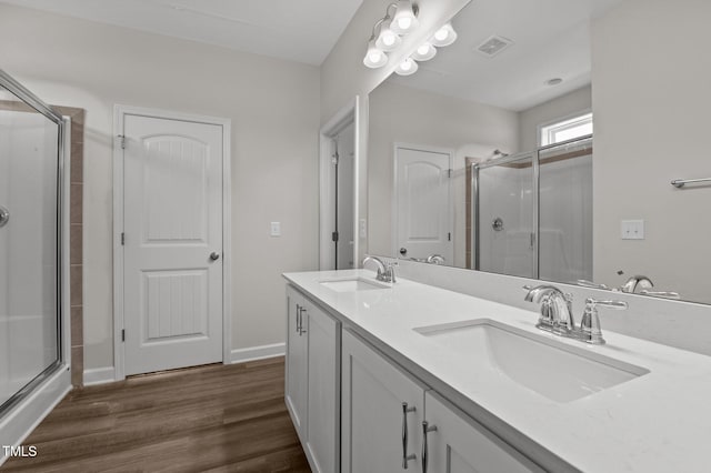 bathroom featuring double vanity, wood finished floors, a sink, and visible vents