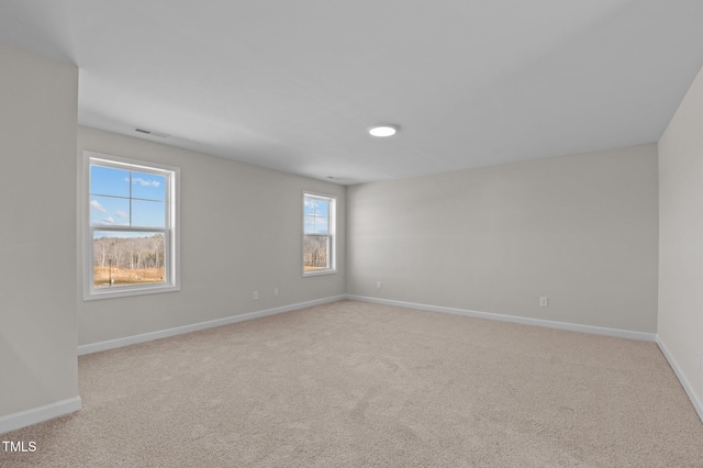 empty room featuring baseboards, visible vents, and light colored carpet